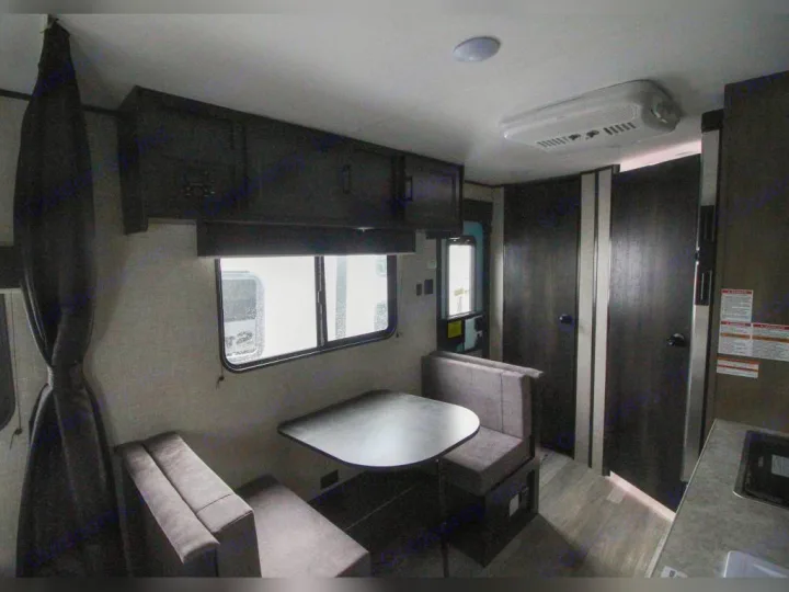 This RV rental interior features a booth dining area, kitchen counter, overhead cabinets, and compact living space.. Jayco Jay Flight SLX 2022
