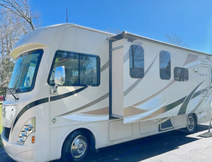 Sunny beige Class A motorhome with slide-out extended, parked outdoors. Perfect for your next RV rental adventure!. Thor A.C.E. 2017