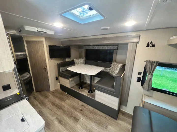 This RV rental interior features a comfortable dinette, wall-mounted TV, and bunk beds, ready for travel.. Forest River Coachmen Catalina Summit 2022