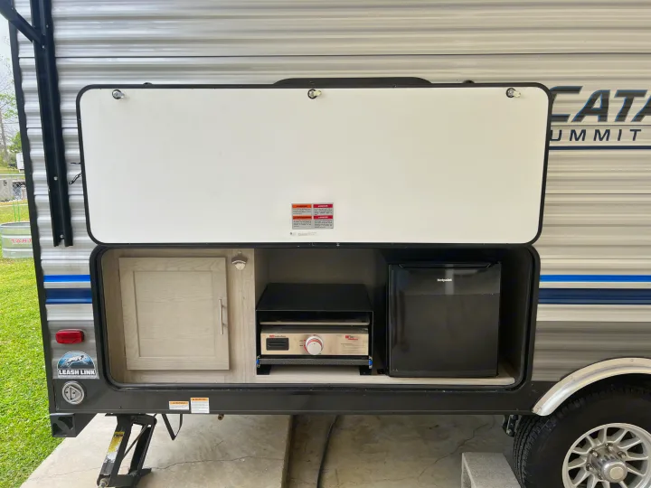 This RV rental features a convenient outdoor kitchen setup, complete with a griddle, mini-fridge, and cabinet.. Forest River Coachmen Catalina Summit 2022