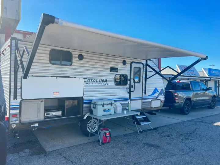 RV rental: A Catalina travel trailer with its awning extended, featuring an outdoor kitchen and a cooler setup. Perfect for camping!. Forest River Coachmen Catalina Summit 2022
