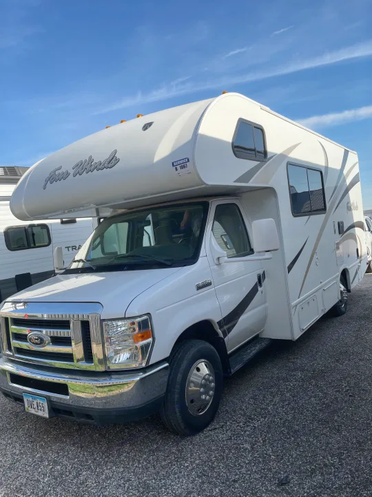 White Ford Four Winds Class C RV for rv rental. This motorhome has a Ford chassis, large windows, and sleek graphics.. Thor Four Winds 2015