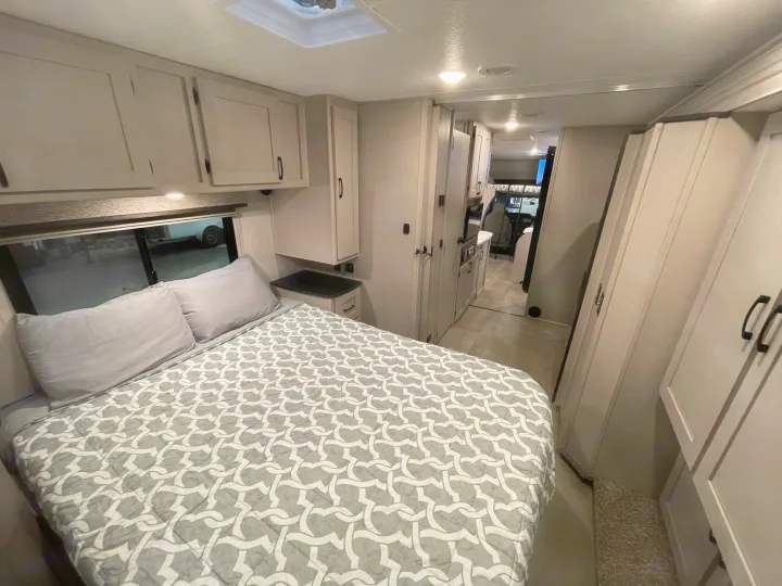 Cozy RV rental bedroom with a modern interior, featuring light cabinets and a comfortable bed for your next adventure.. Coachmen Freelander 2024