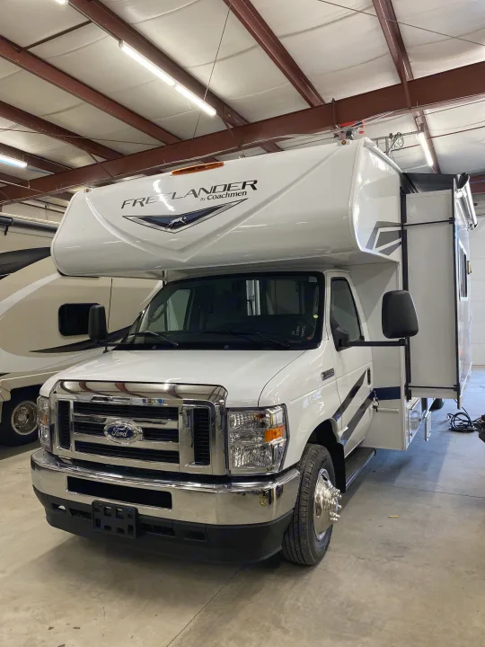 White "Freelander by Coachmen" RV on a Ford chassis, ready for rv rental in a brightly lit indoor space.. Coachmen Freelander 2024