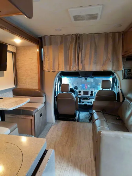 Spacious RV rental interior showing front cockpit, dinette, and sofa lounge areas. Ideal for travel.. Thor Quantum 2021