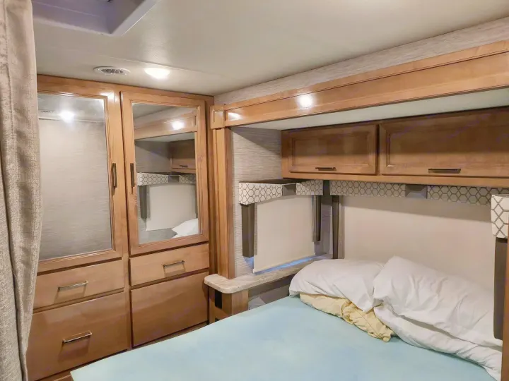 RV rental bedroom interior with cabinets, bed, and mirrored wardrobe for compact living.. Thor Quantum 2021