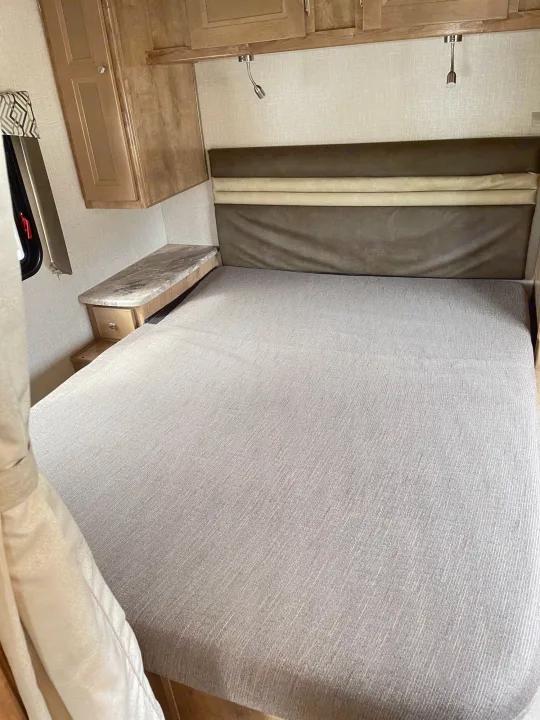 RV rental: Compact RV bedroom with bed, headboard, overhead storage, bedside table & reading lights.. Coachmen Leprechaun 2020