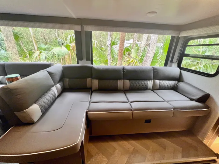 Spacious RV rental interior featuring a comfortable U-shaped couch and large windows with a lush natural view.. Forest River Wildwood X-Lite 2022