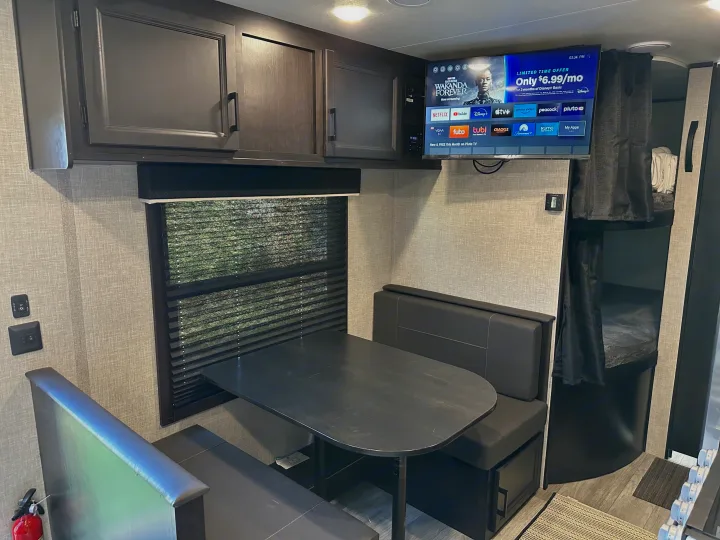 Cozy RV rental interior with dinette, entertainment TV, and bunk beds. Perfect for family adventures.. Jayco Jay Flight SLX 2022
