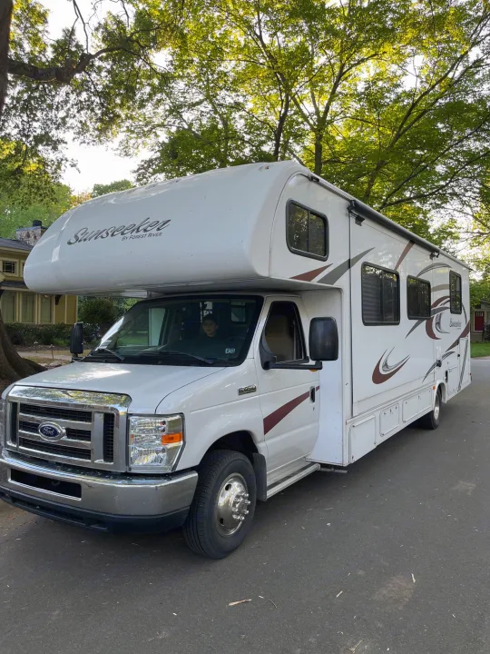 This white Sunseeker Class C RV rental, built on a Ford chassis, is parked on an asphalt street, ready for adventure.. Forest River Sunseeker 2016