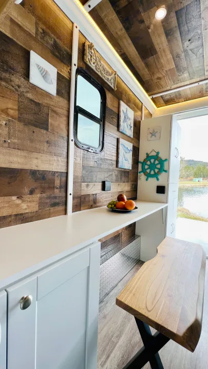 Cozy RV rental interior with rustic wood walls, coastal decor, functional counter, and scenic lake views for glamping.. Cargo Pro Stealth 2021