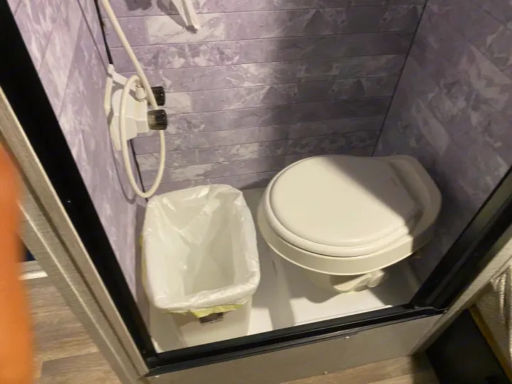 Inside an RV rental: a compact wet bath with a white toilet, small trash can, and wall-mounted shower head for efficient use of space.. Braxton Creek Bushwhacker Plus 2022