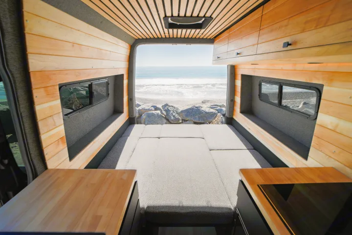 Stunning beach view from a cozy camper van RV rental with wood interior & comfy bed. Your adventure awaits!. Mercedes Sprinter 2021