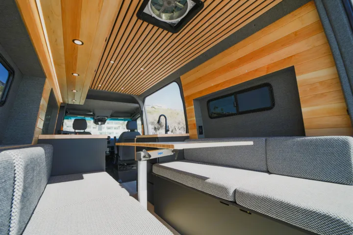 Spacious RV rental camper van interior showcasing a wood slat ceiling, gray seating, and versatile Lagun table system.. Mercedes Sprinter 2021