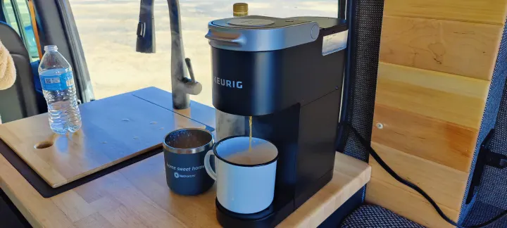 Enjoying coffee in our RV rental! Keurig brews a fresh cup on the compact kitchen counter with water bottle & sink.. Mercedes Sprinter 2021