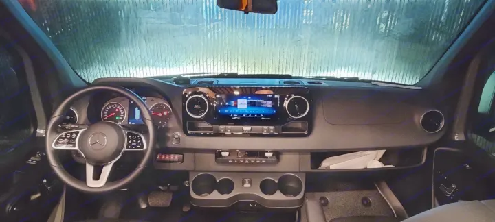 Interior of a modern Mercedes-Benz RV rental, featuring the dashboard, steering wheel, and infotainment screen.. Mercedes Sprinter 2021