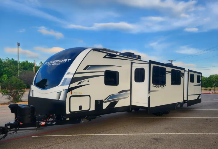 Modern white & black Passport travel trailer, ideal for your next RV rental adventure, parked with slide-outs extended.. Keystone RV Passport GT Ultra Lite 2023
