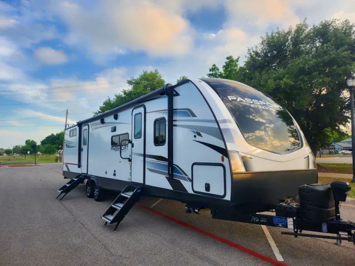 Sleek Passport GT Series RV, ideal for rv rental, parked in a sunny lot with steps extended for easy access.. Keystone RV Passport GT Ultra Lite 2023