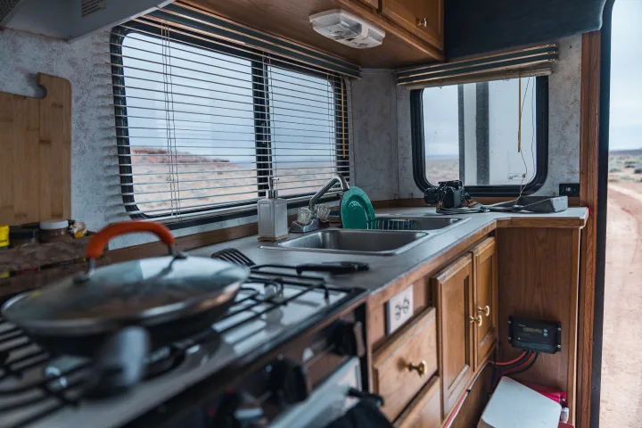 RV rental kitchen: A functional RV interior showing a stove, sink, and cabinets, with a desert landscape visible through the windows.. Ford Other 1996
