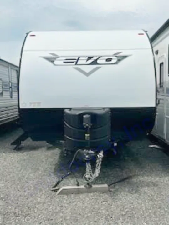 Front of a white EVO travel trailer, ready for your RV rental adventure. Hitch & propane tanks visible, ideal for camping trips!. Forest River Evo 2023