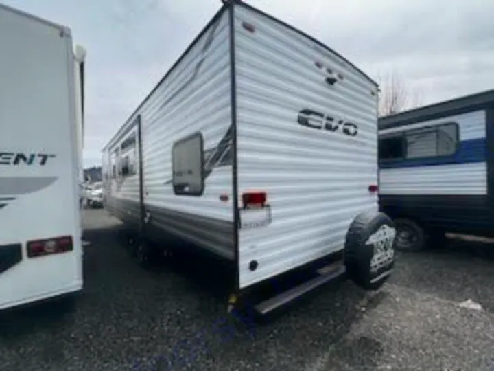 A white EVO travel trailer RV, perfect for your next RV rental. This camper is shown parked outdoors.. Forest River Evo 2023