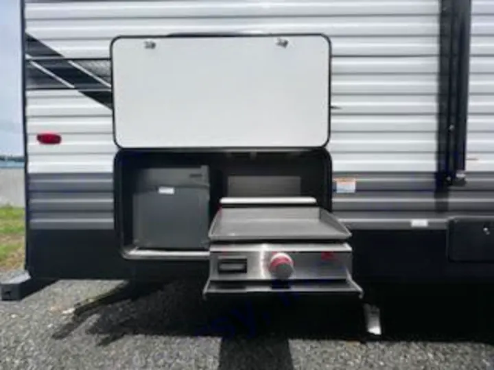 This RV rental's side compartment reveals an outdoor kitchen with a pull-out griddle, perfect for camping meals.. Forest River Evo 2023