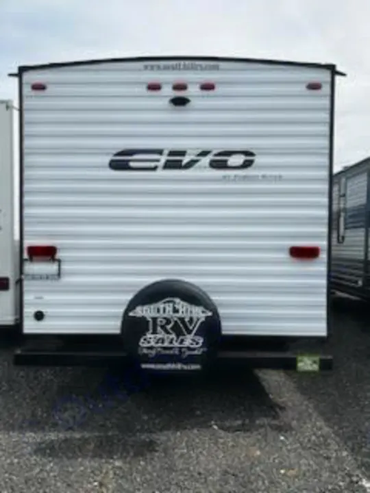 Rear view of a white Evo travel trailer RV with a spare tire cover. Ideal for RV rental and sales, ready for your next adventure.. Forest River Evo 2023