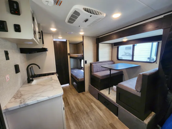 Spacious RV rental interior featuring a modern kitchen, cozy dining area, and practical bunk beds. Perfect for family adventures!. Jayco slx 2023