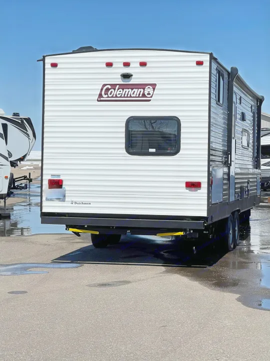 Rear view of a white Coleman Dutchmen travel trailer, ideal for rv rental. Parked on a wet asphalt lot.. Coleman Lantern 242BH 2022