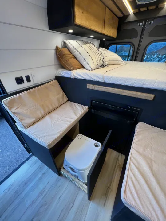 RV rental: Camper van interior with a comfy bed, bench seating, and a discreet pull-out portable toilet.. Dodge Ram Promaster 2500 2022