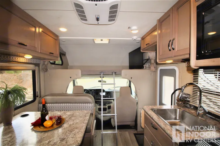 Modern RV rental interior with a bright kitchen, comfortable dining area, and a ladder leading to the over-cab bunk.. Thor Motor Coach Freedom Elite 2018
