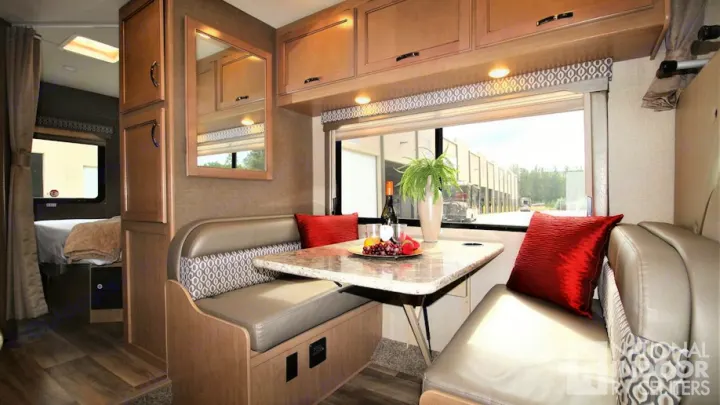 Inside this **rv rental**, a welcoming dinette with plush seating and wood finishes transitions to a private bedroom area.. Thor Motor Coach Freedom Elite 2018