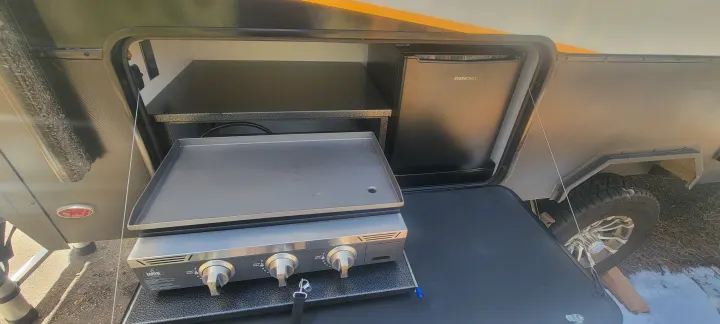 Enjoy an RV rental with this convenient outdoor kitchen, featuring a griddle and mini-fridge for camp meals.. Ember Overland 2023