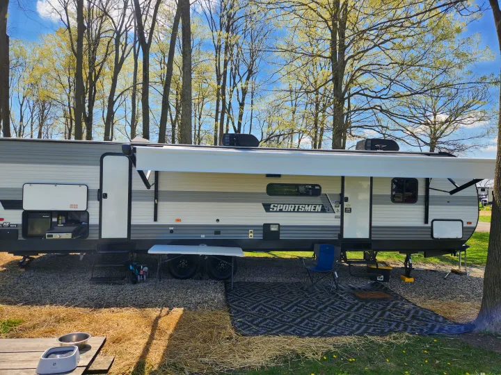 Enjoy this inviting RV rental: a modern travel trailer with outdoor kitchen, awning, and pet amenities at a scenic campsite.. Sportsmen Other 2022