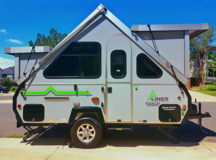Gray A-frame pop-up travel trailer for rv rental. Its distinctive triangular roof and windows are visible.. A-liner Classic 2022