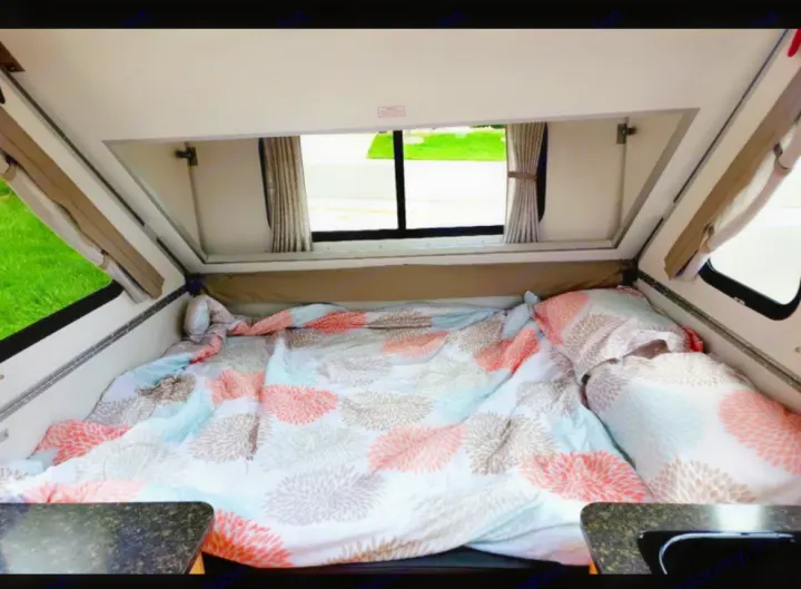 RV rental: Interior of a cozy pop-up camper featuring a bed with colorful floral bedding & bright windows.. A-liner Classic 2022
