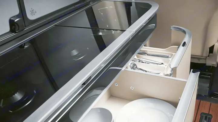 RV rental kitchen: a sleek black cooktop and pull-out drawers organized with silverware and white plates.. Mercedes Class V Marco Polo 2023