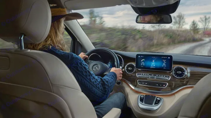 Inside a Mercedes-Benz, a driver in a hat on a rural road. Modern dashboard and large screen visible, ready for an RV rental.. Mercedes Class V Marco Polo 2023