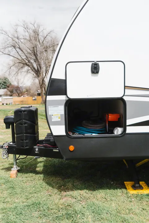 RV rental trailer with open storage, revealing hoses & gear.. Dutchmen Astoria 2022