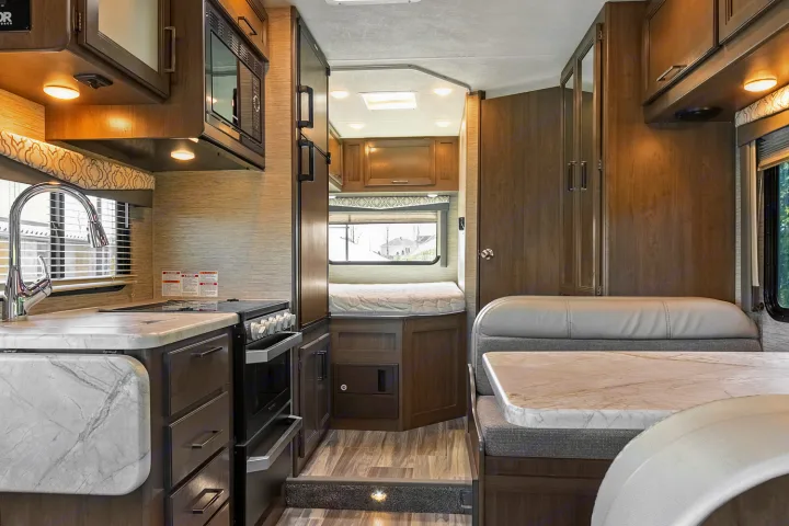 Spacious rv rental interior featuring a modern kitchen, comfy dinette, and cozy rear bedroom area.. Thor Freedom Elite 2021