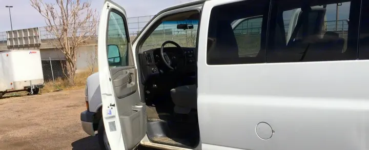 White Chevrolet Express-style van for RV rental has its driver's door open, showing the interior.. Chevrolet Express 1500 2009