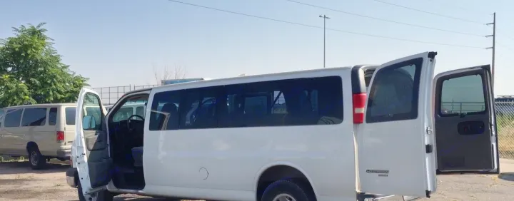 Spacious white and beige passenger vans, some with open doors, ready for an RV rental adventure or group transport.. Chevrolet Express 3500 2005