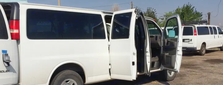 White passenger vans, similar to those for rv rental or large group transport, with doors open.. Chevrolet Express 3500 2005