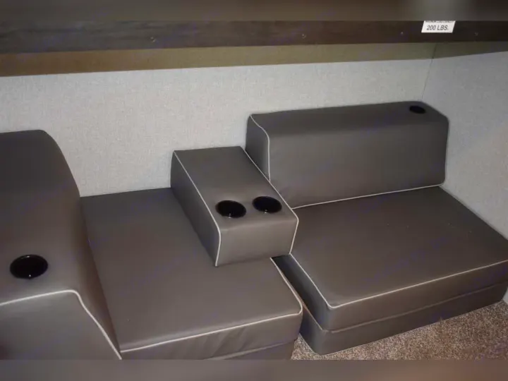 Modular gray cushions with cup holders create versatile seating/sleeping in this RV rental. Note the 200 lbs limit sign.. Forest River Surveyor 2021