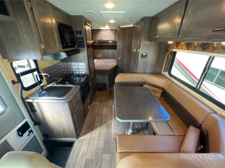 View of a modern RV rental interior featuring a full kitchen, comfortable dining booth, and rear sleeping area.. Winnebago Minnie Winnie 2019
