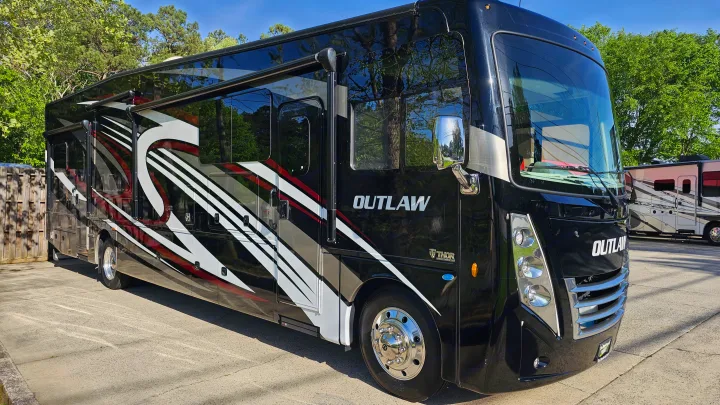Sleek black Outlaw RV motorhome, ideal for an rv rental adventure with its striking red & white graphics.. Thor Motor Coach Outlaw 2023