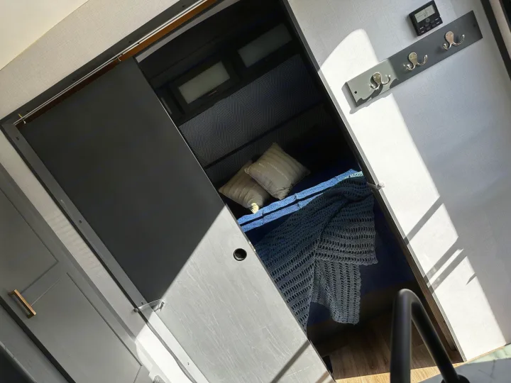 This RV rental offers a compact sleeping nook with a sliding door, cozy bedding, and a wall-mounted coat rack.. Keystone RV Bullet Ultra Lite 2022