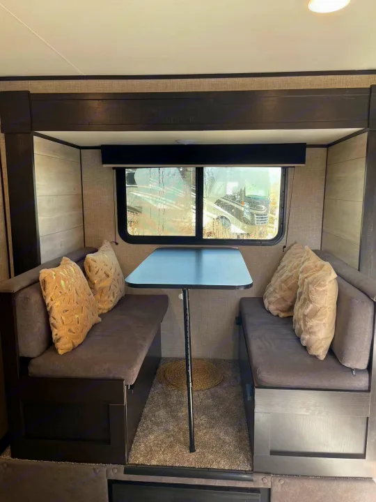 RV rental dinette interior: a cozy, compact space with two gray cushioned benches, a table, and light walls.. Jayco Jay Flight SLX 2022