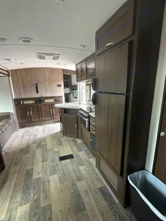 Clean RV rental interior featuring a modern kitchen area with large fridge, stove, and wood-look flooring.. Keystone RV Springdale 2021