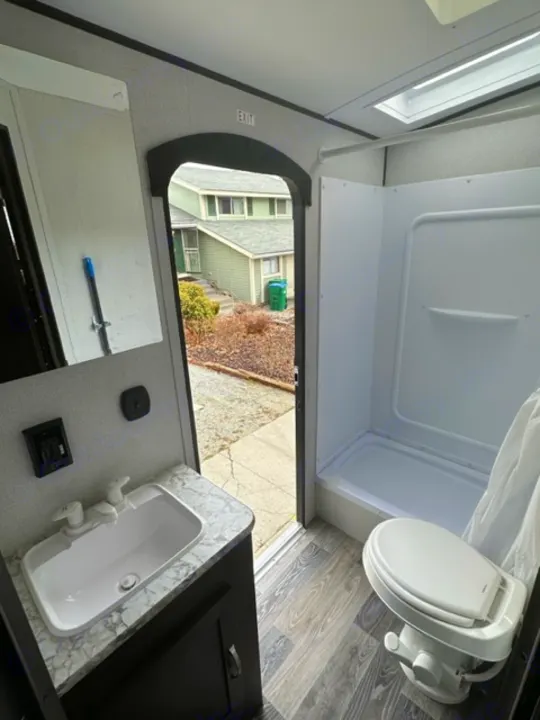 RV rental interior showcasing a compact bathroom with toilet, sink, and shower stall. Perfect for your next adventure.. Keystone RV Springdale 2021
